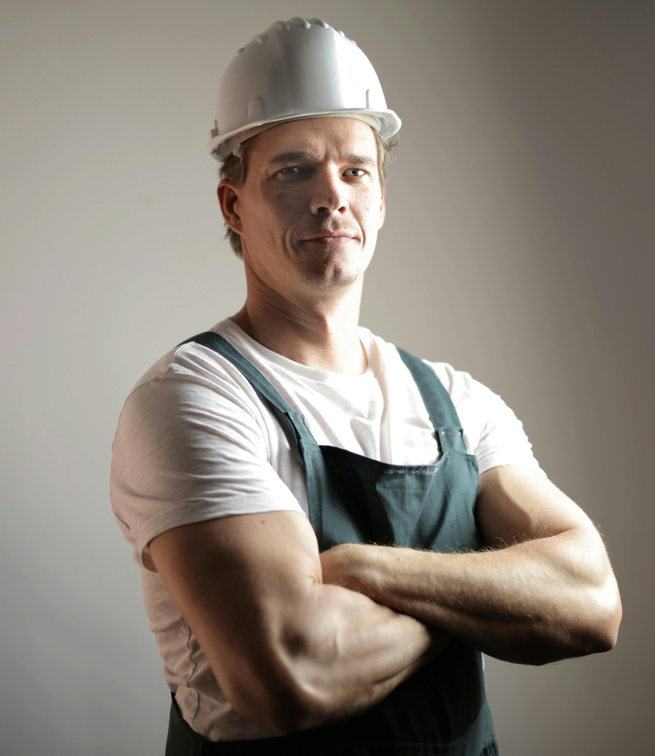 Portrait of a confident construction worker in a studio setting, arms crossed.